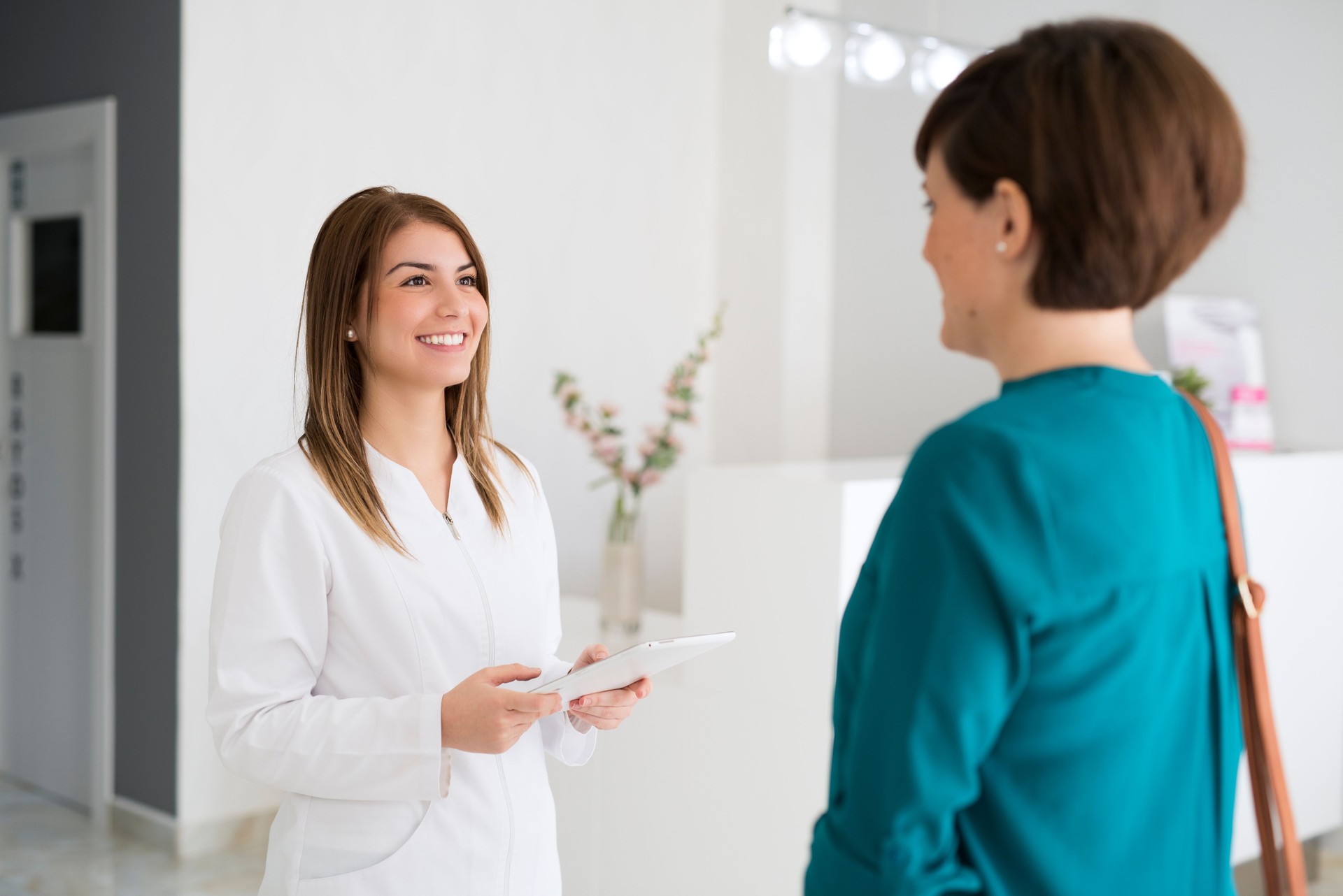female receptionist in medical clinic consulting tablet in waiting room